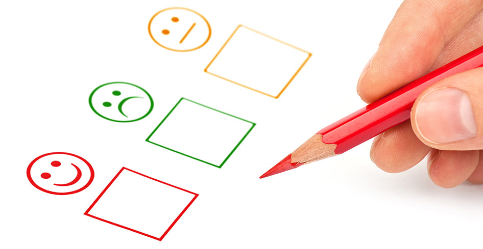 Stock photo of three check boxes for :)  :(  and :|  and a person's hand with a pencil hovering nearby