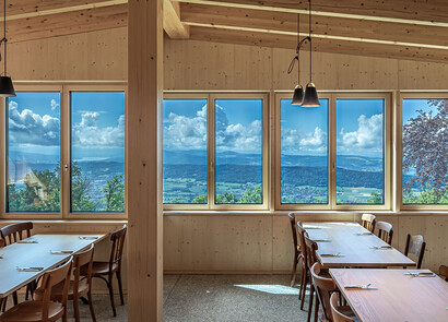 Dining tables in a room with custom smart glass windows overlooking mountain range. 