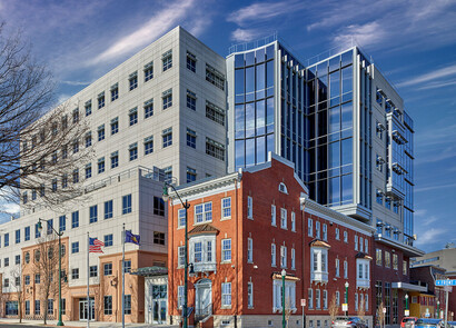 Building facade with smart windows from left to right on a large brick and modern glass building with a shot of the clouds and outdoors.