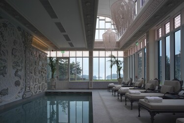 Interior view of a fancy pool room with loungers and glass exterior walls.