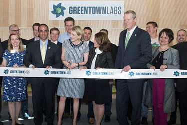 Greentown Labs team stands in front of ribbon for ribbon cutting ceremony.
