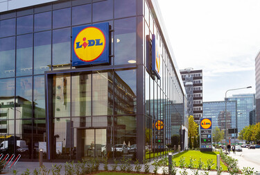 Lidl building facade with smart windows from left to right on a large modern glass building with a shot of the clouds and city.