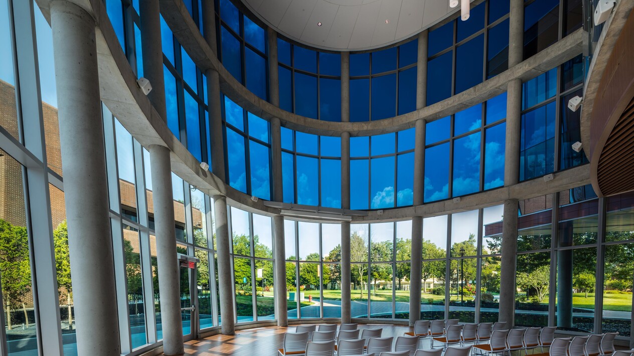 Large rounded room with open space filled with chairs and custom curved smart glass windows. 