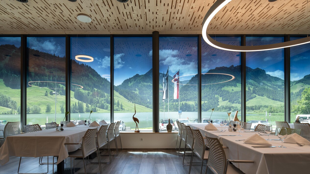 Interior view of a restaurant or banquet room with floor to ceiling windows looking at a stunning view of nature.