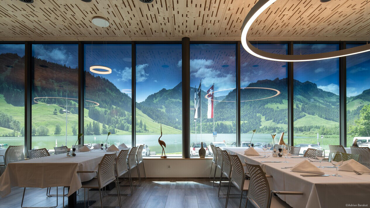 Interior view of a restaurant or banquet room with floor to ceiling windows looking at a stunning view of nature.