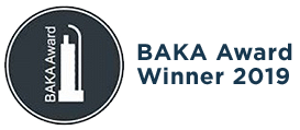 A black circle with white text saying BAKA Award and a white ?object outline, then text outside the circle saying BAKA Award Winner 2019