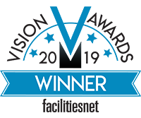 Blue and black and white text logo saying "Vision V Awards Winner 2019 facilitiesnet"