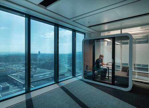 Interior office looking outside- walls of tinted glass, an interior room of tinted glass within the room, with a person sitting at a table