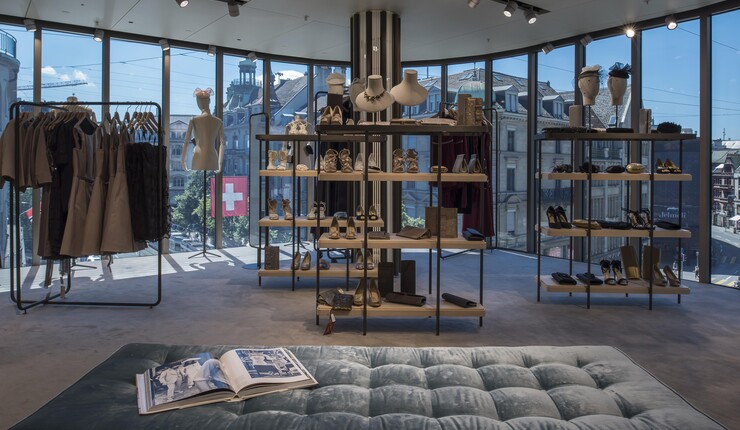 An interior store view with glass walls. There are shoes, dresses and jewelry throughout the space for sale.