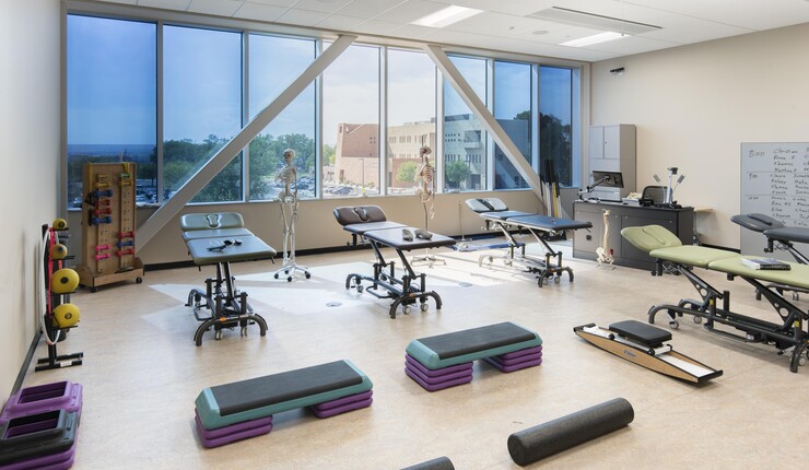 Interior workout studio view, with a wall of tinted glass. Workout equipment dispersed around the room.