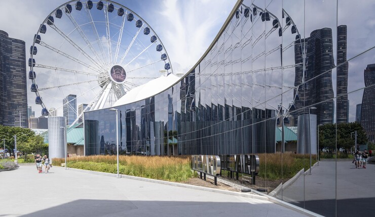 Exterior of a glass building with a ferris wheel in the background.