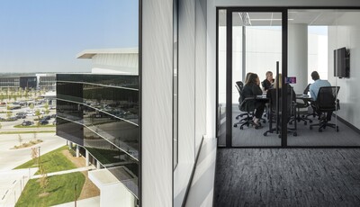 Exterior building facade with smart windows from left to right on a large modern glass building and interior office space with coworkers collaborating.