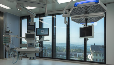 Interior of medical room with equipment and smart glass floor to ceiling windows overlooking the town. 