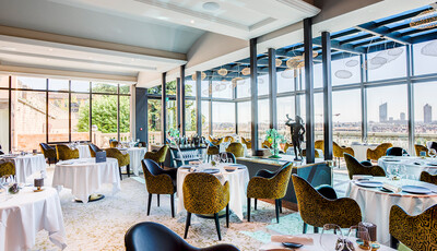 Interior of restaurant with unique dining space and custom smart glass windows overlooking the city.