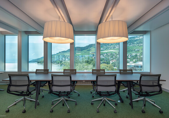 Interior of meeting room with smart glass windows overlooking the water and mountains. 