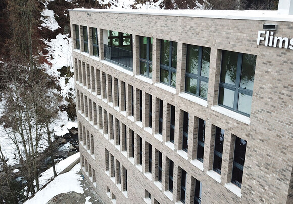 Building facade with smart windows from left to right on a brick building with snow in the background.