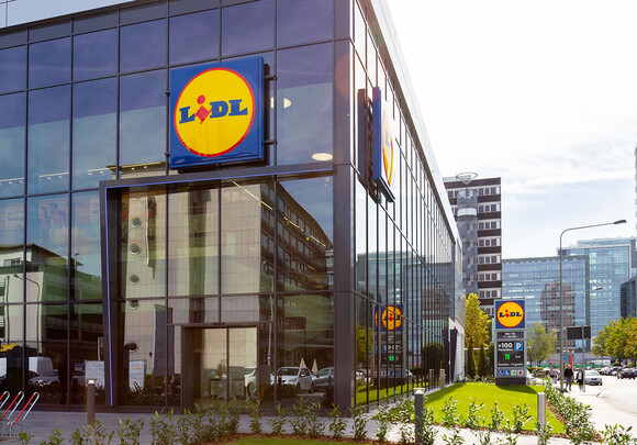 Lidl building facade with smart windows from left to right on a large modern glass building with a shot of the clouds and city.