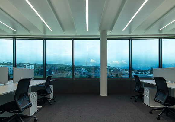 Common office space with smart glass windows overlooking town. 
