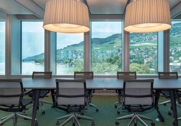 Interior of meeting room with smart glass windows overlooking the water and mountains. 